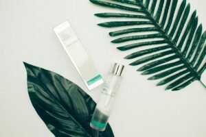 Flat lay of skincare toner and packaging with green leaves on a white background.